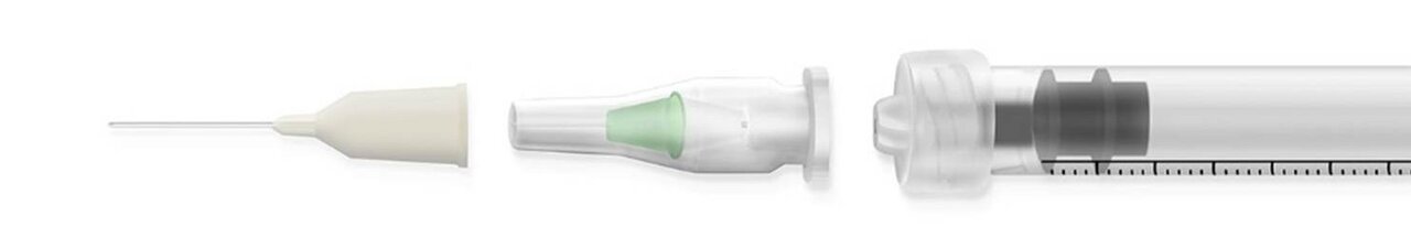 Eine Spritze mit einer transparenten Kammer zur Medikamentenaufnahme, einem sichtbaren Kolben und einer feinen Nadel rechts. Die Nadel ist mit einer Schutzkappe versehen. Die Darstellung zeigt die Komponenten der Spritze in einer linearen Anordnung.